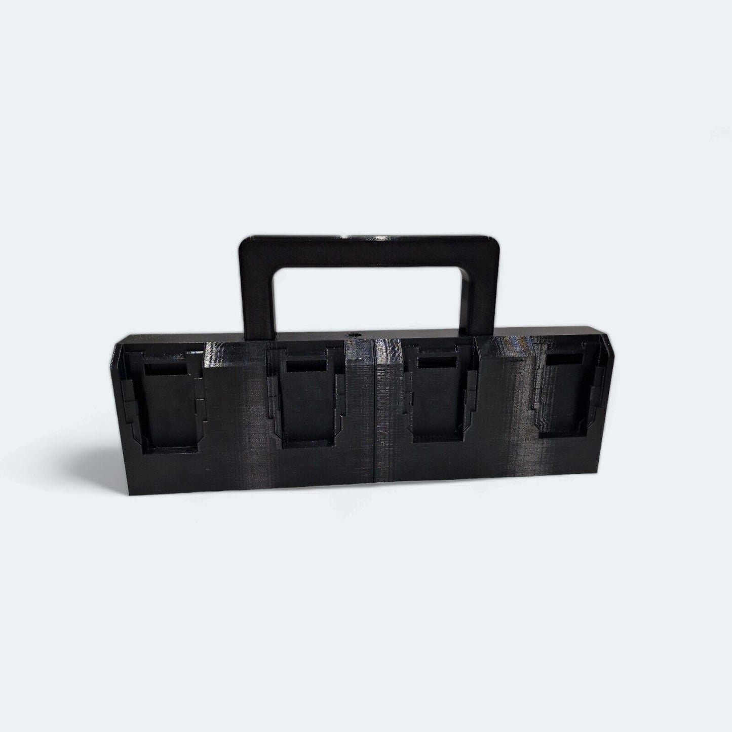 The 8x Battery Basket Carrier Caddy Holder for DeWALT, crafted by Ice3Dprints, is a black rectangular 3D-printed device featuring four square compartments and a central handle for easy transport. Perfect for organizing items, it is displayed against a plain background.