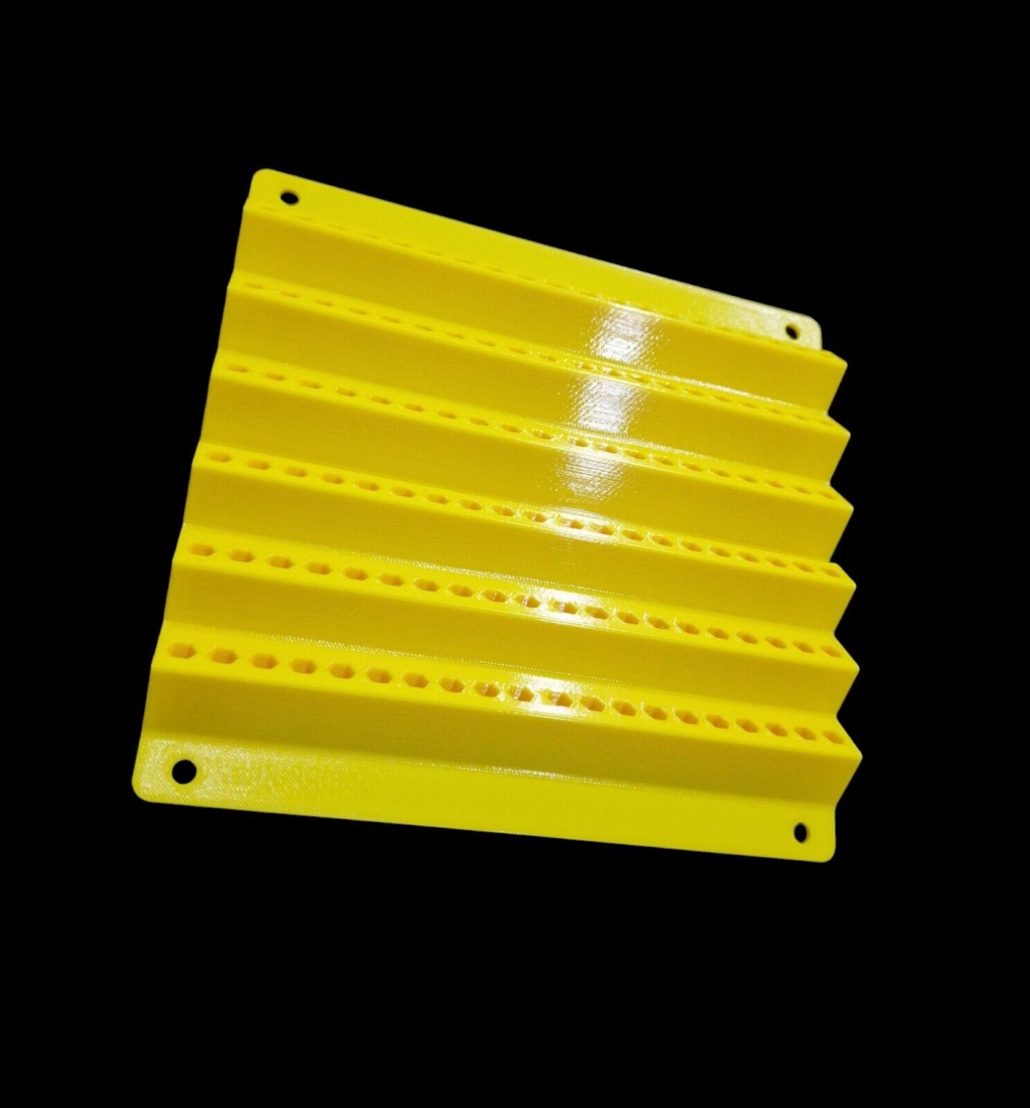 This yellow, rectangular 120 HOLES SCREWDRIVER BIT HOLDER by Unbranded is crafted from durable materials. It features parallel ridges and rows of small holes, resembling a textured panel against a black background. Its glossy surface reflects light, and four small corner holes suggest it's designed for wall mounting or potentially as a screwdriver bit holder with a hex shank of 6.35mm (1/4").