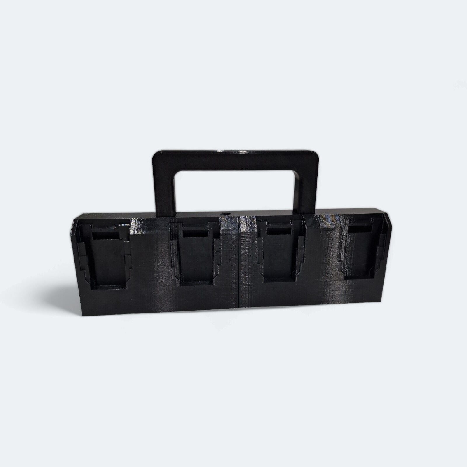The 8x Battery Basket Carrier Caddy Holder for DeWALT, crafted by Ice3Dprints, is a black rectangular 3D-printed device featuring four square compartments and a central handle for easy transport. Perfect for organizing items, it is displayed against a plain background.