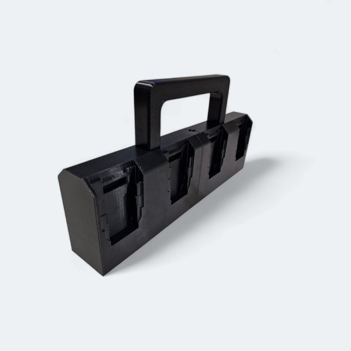 A black, rectangular plastic holder featuring a convenient handle and designed with four compartments is perfect as an 8x Battery Basket Carrier Caddy Holder for DeWALT. Produced by Ice3Dprints, it's ideal for organizing your lithium-ion battery caddy collection against a plain white background.