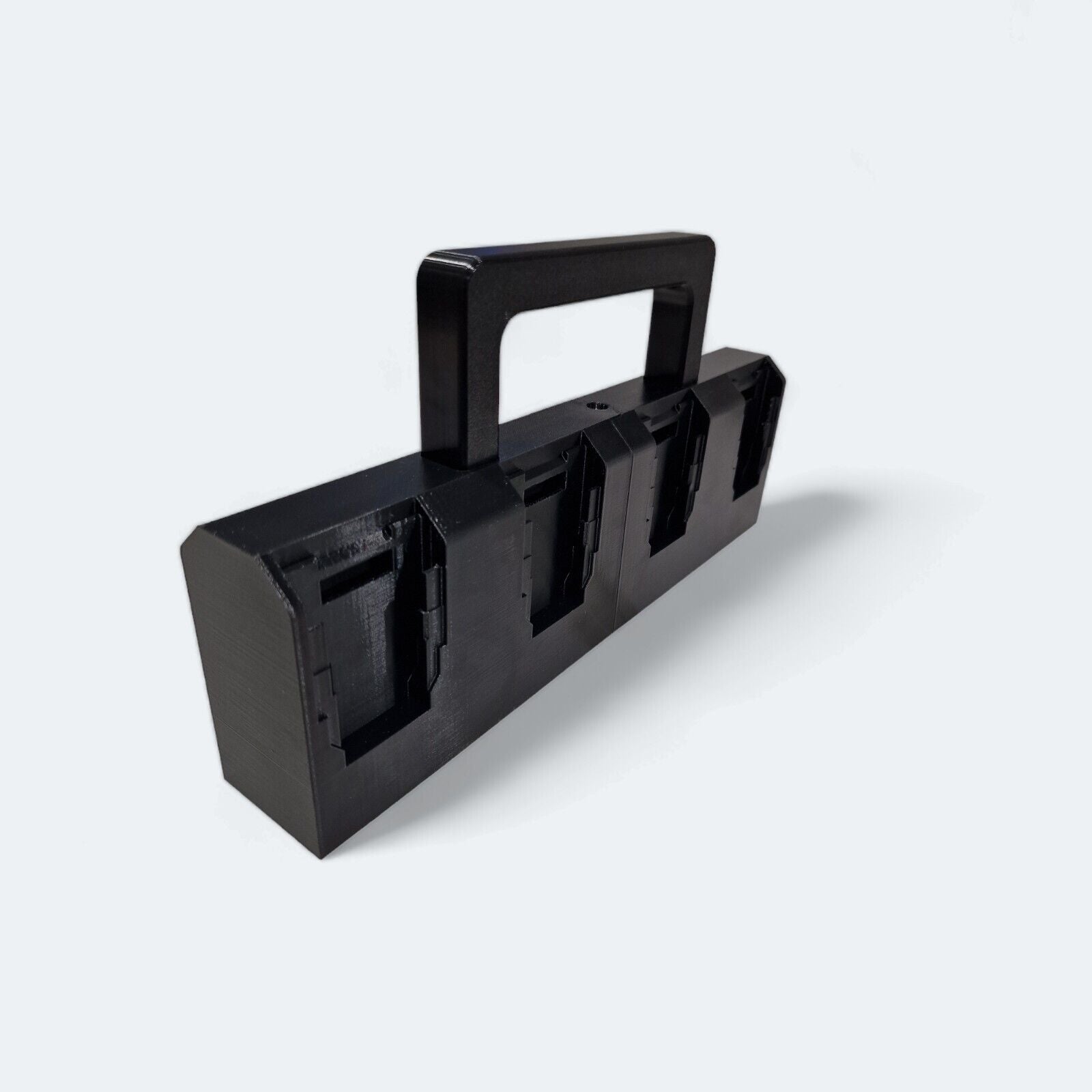 A black, rectangular plastic holder featuring a convenient handle and designed with four compartments is perfect as an 8x Battery Basket Carrier Caddy Holder for DeWALT. Produced by Ice3Dprints, it's ideal for organizing your lithium-ion battery caddy collection against a plain white background.